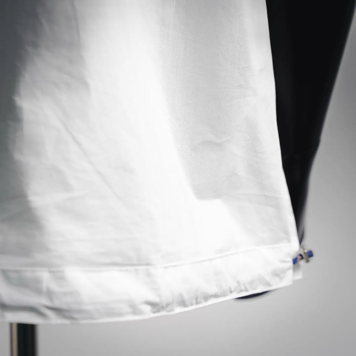 White shirt hem with stitching and blue drawstring tag