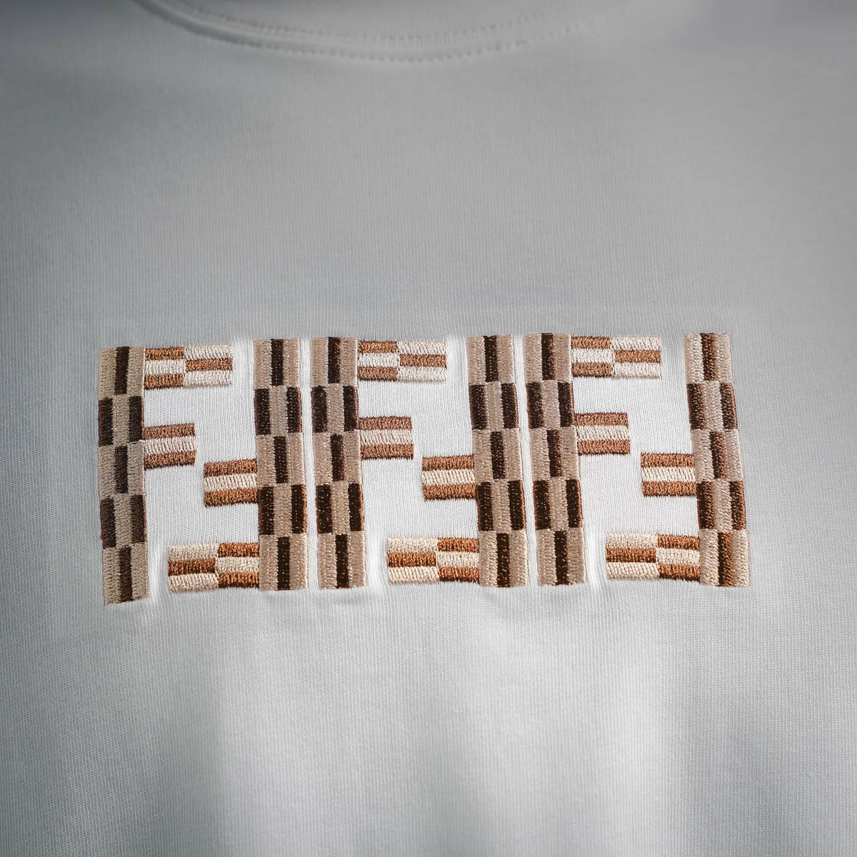 Embroidered multicolor geometric logo detail on white T-shirt