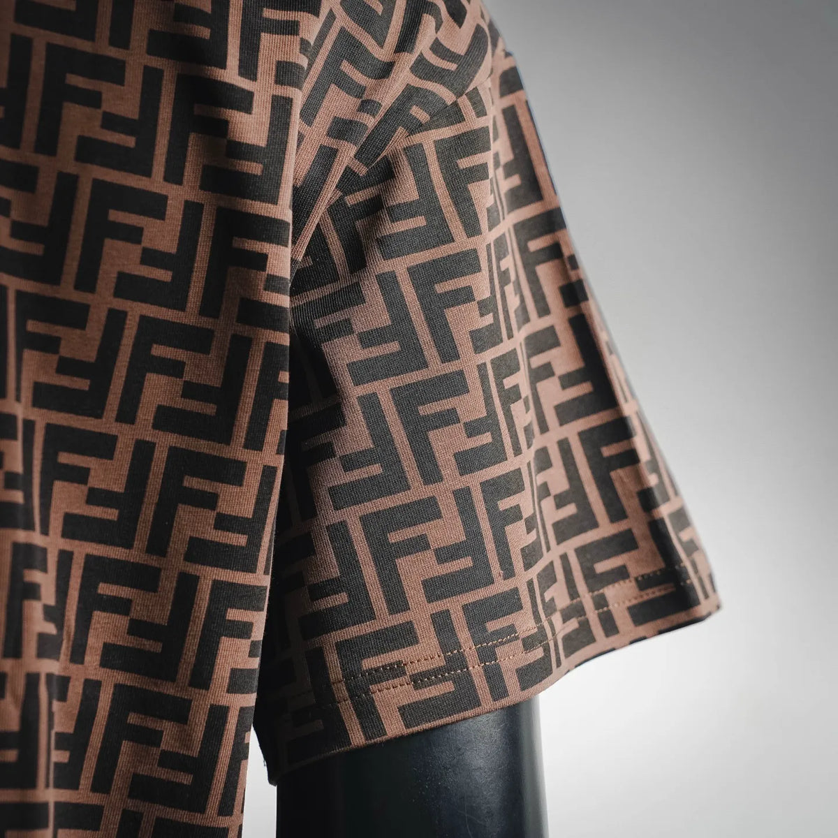 Side view of brown Fendi FF patterned T-shirt with orange trim at sleeve and hem