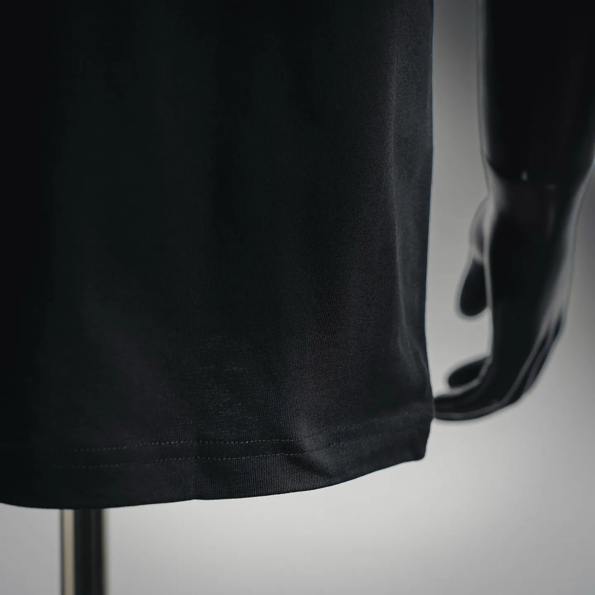Black T-shirt hem and side seam stitching close-up
