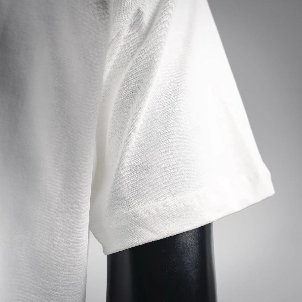 White short-sleeve T-shirt fabric close-up with visible seam and drape