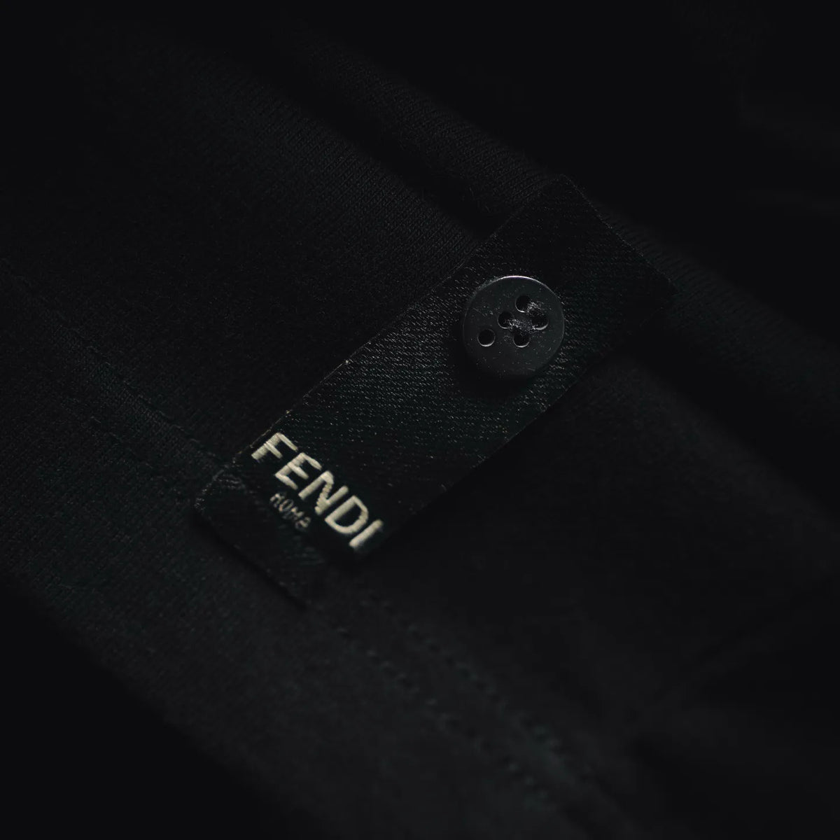 Fendi black fabric label with small button-style closure on inner neckline