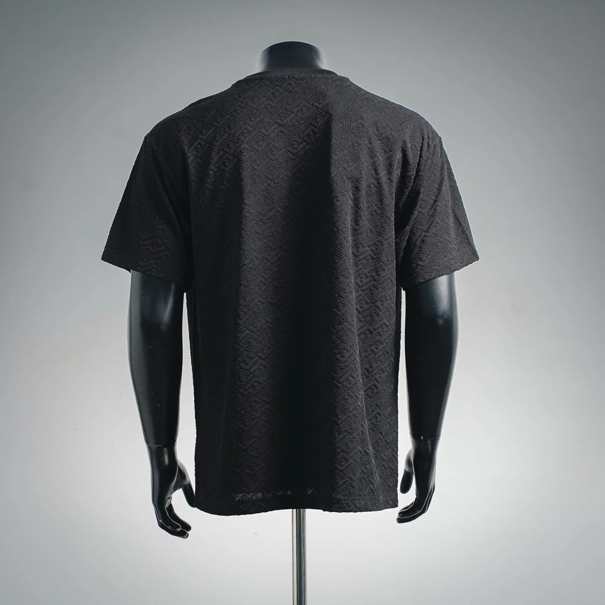 Dark short-sleeve shirt with textured allover logo pattern, back view