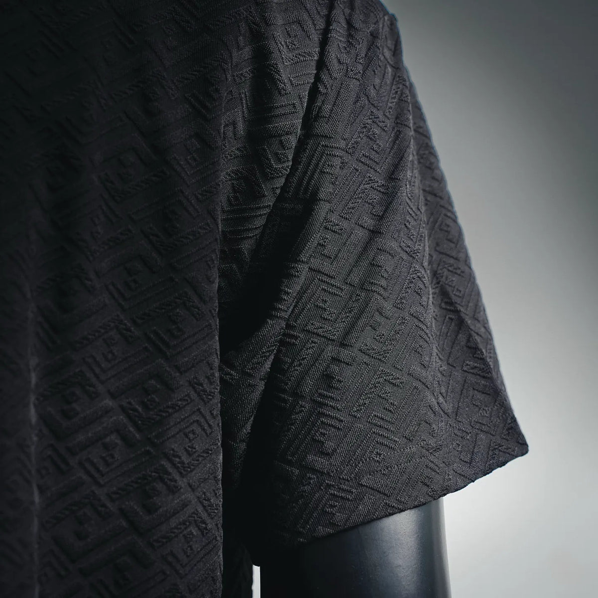 Dark short-sleeve shirt shoulder and sleeve with textured allover logo pattern