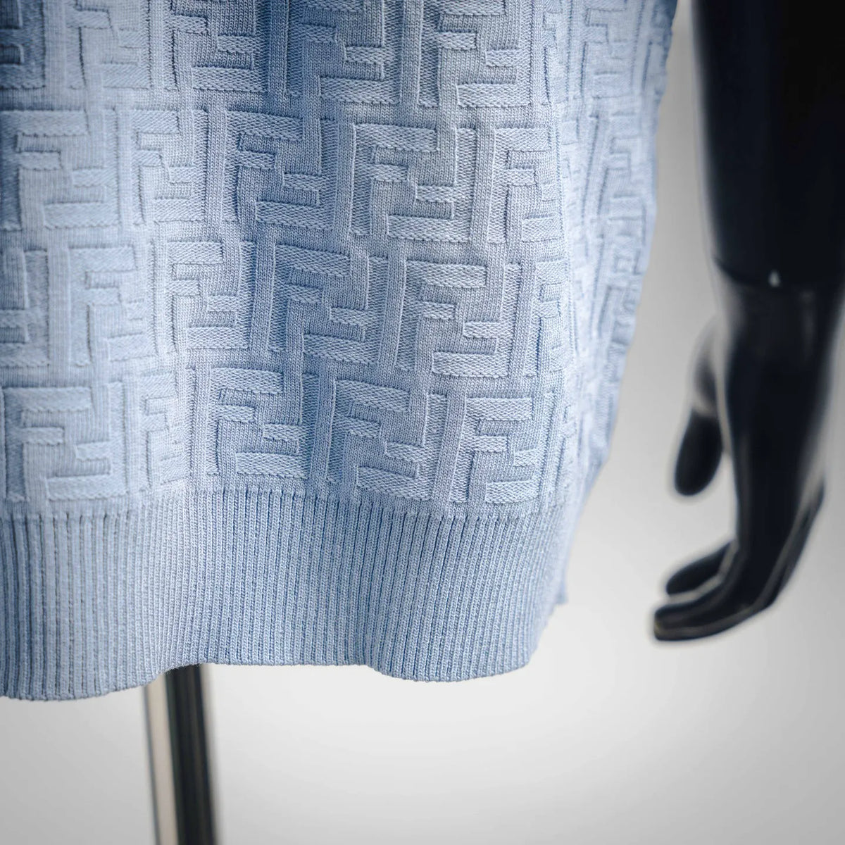 Light blue Fendi knit polo shirt close-up of embossed logo pattern