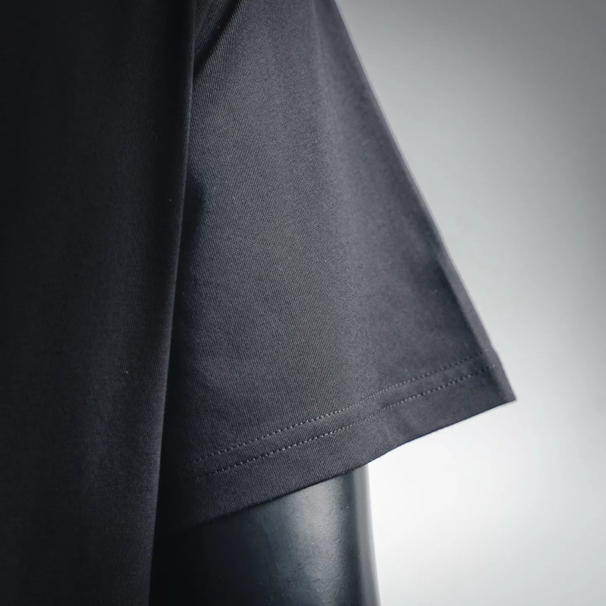 Black T-shirt sleeve hem close-up with stitched cuff edge