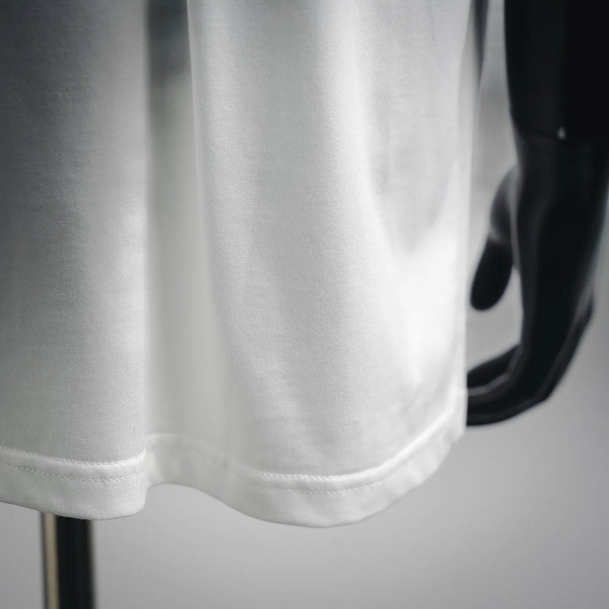 White short-sleeve T-shirt hem detail with stitched cuff and soft fabric drape.