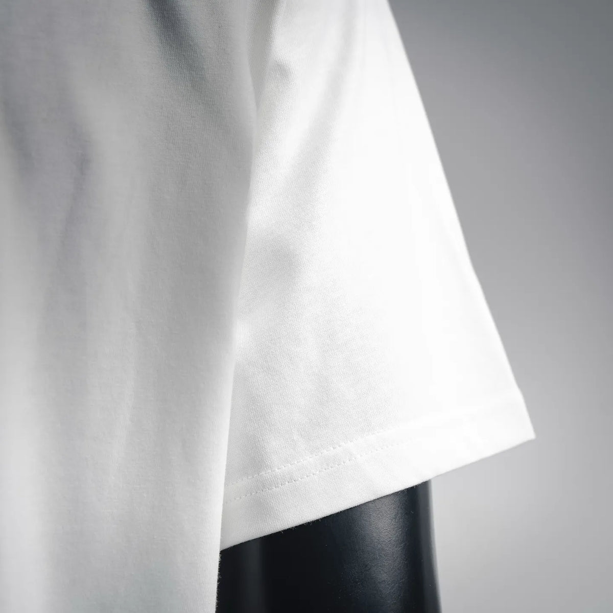 White T-shirt sleeve and side seam detail with clean stitched hem.