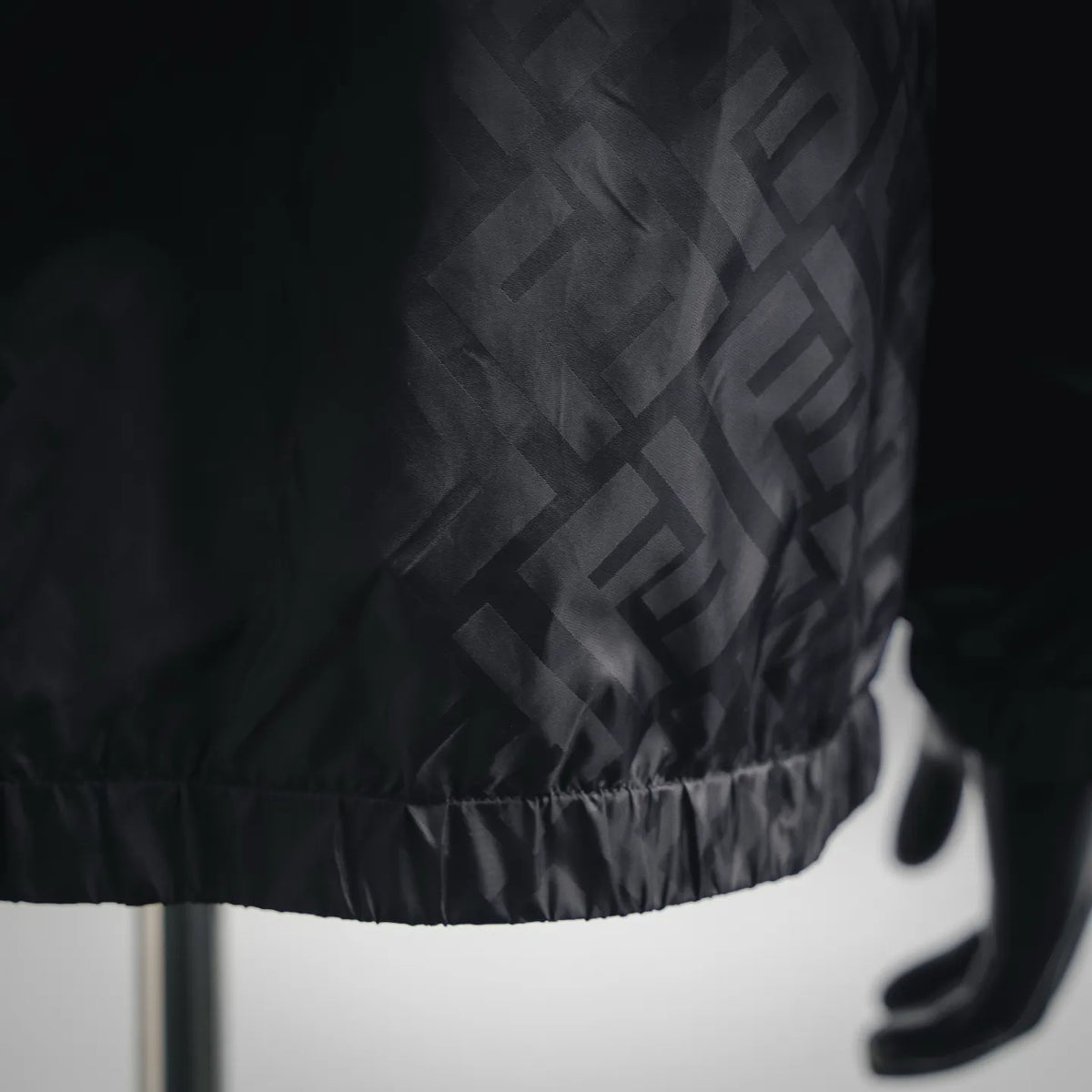 Black coat hem with elastic gathers and allover FF logo pattern