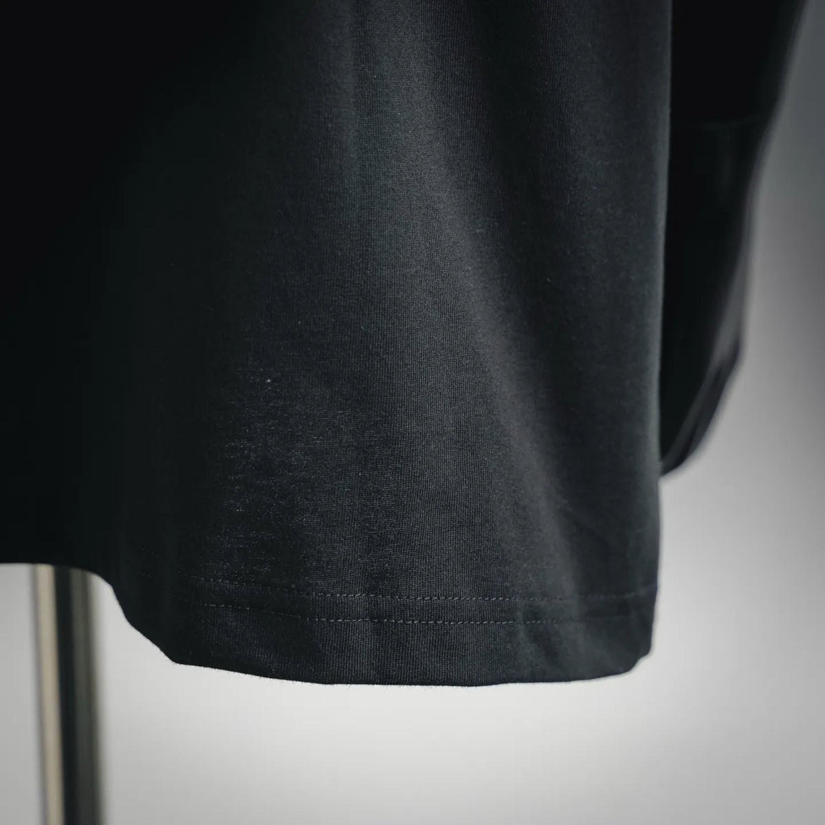 Black T-shirt hem close-up with visible stitching and smooth knit fabric