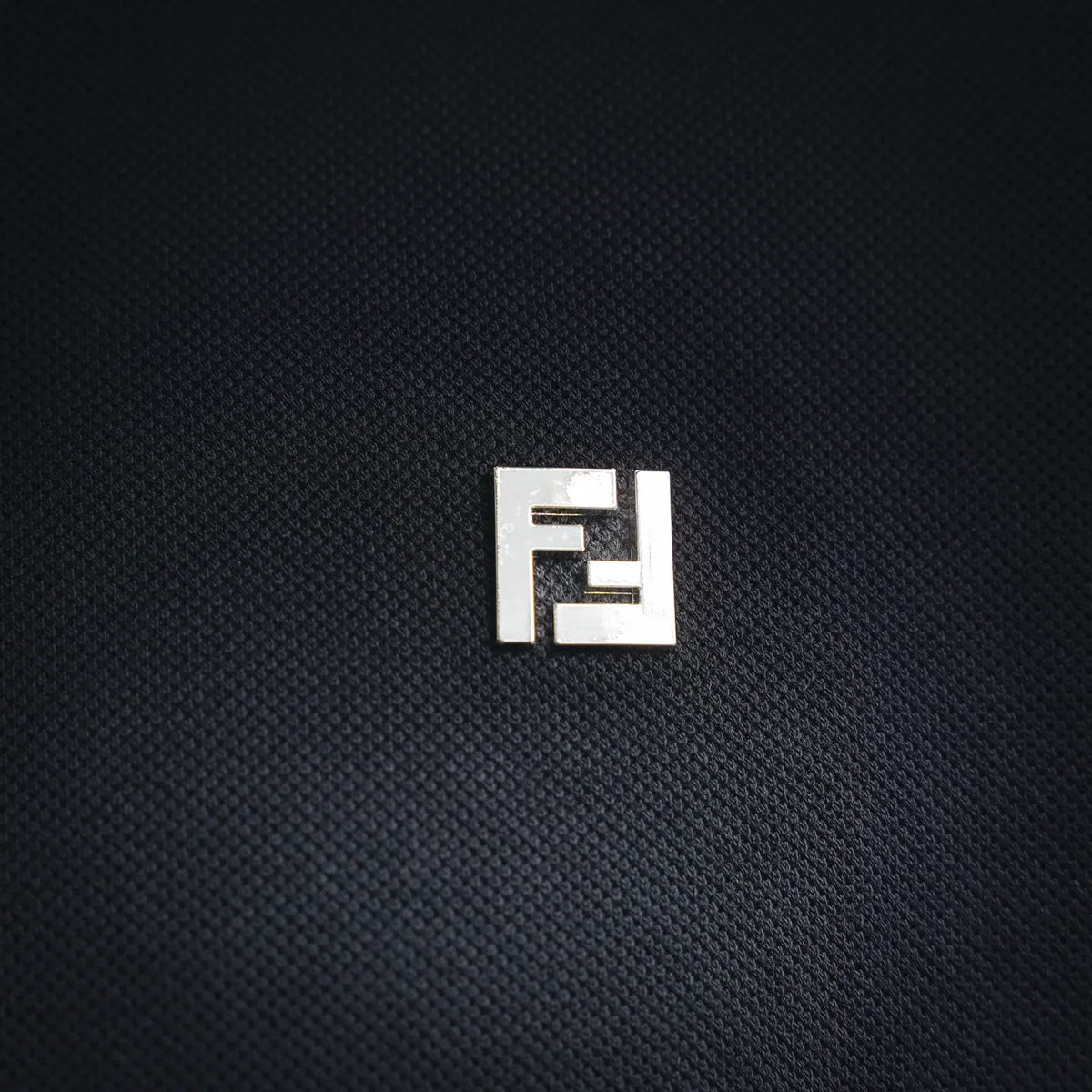 Fendi FF logo patch on dark polo shirt chest.