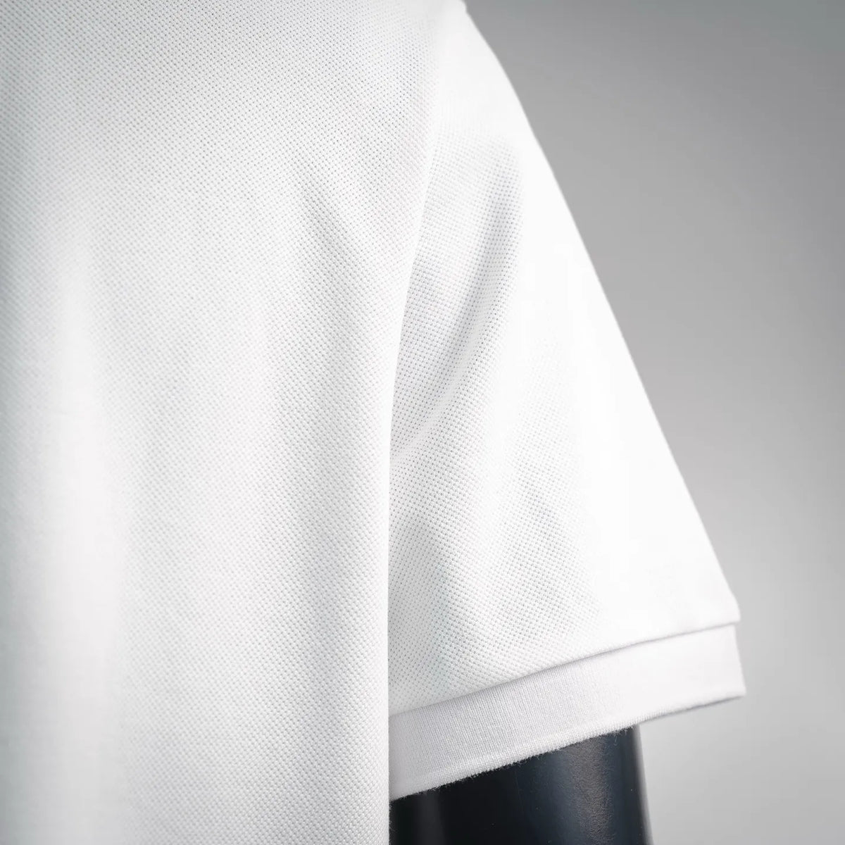 White polo shirt sleeve and cuff close-up with textured fabric detail.