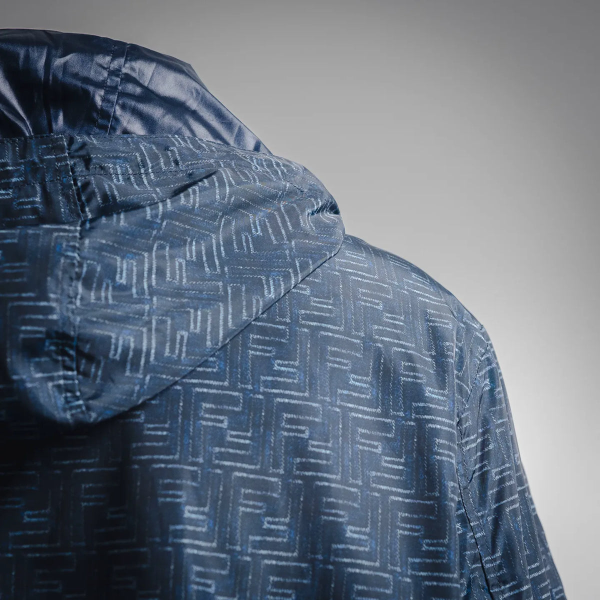 Close-up of dark blue hooded jacket fabric with Fendi FF monogram pattern
