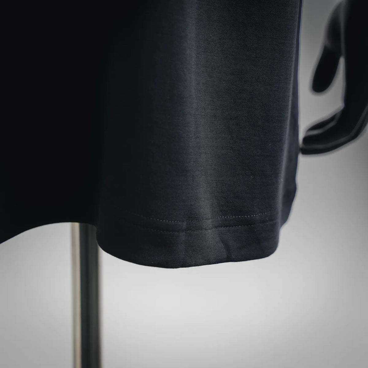 Black short-sleeve T-shirt fabric and stitched hem near bottom edge