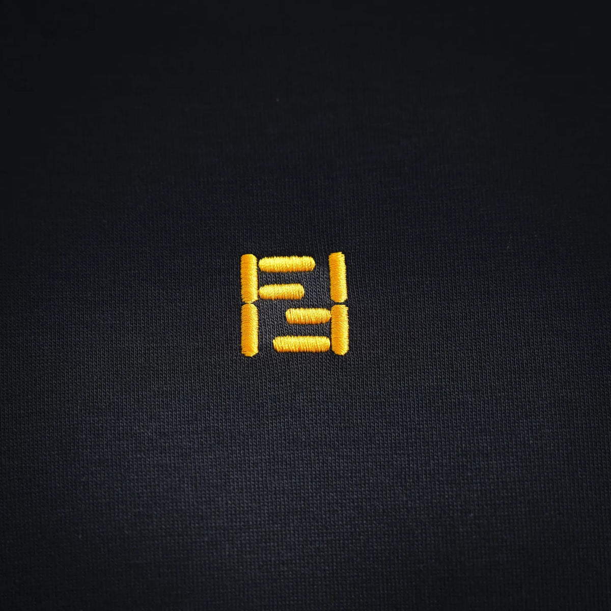 Black T-shirt with small yellow Fendi logo patch on upper chest