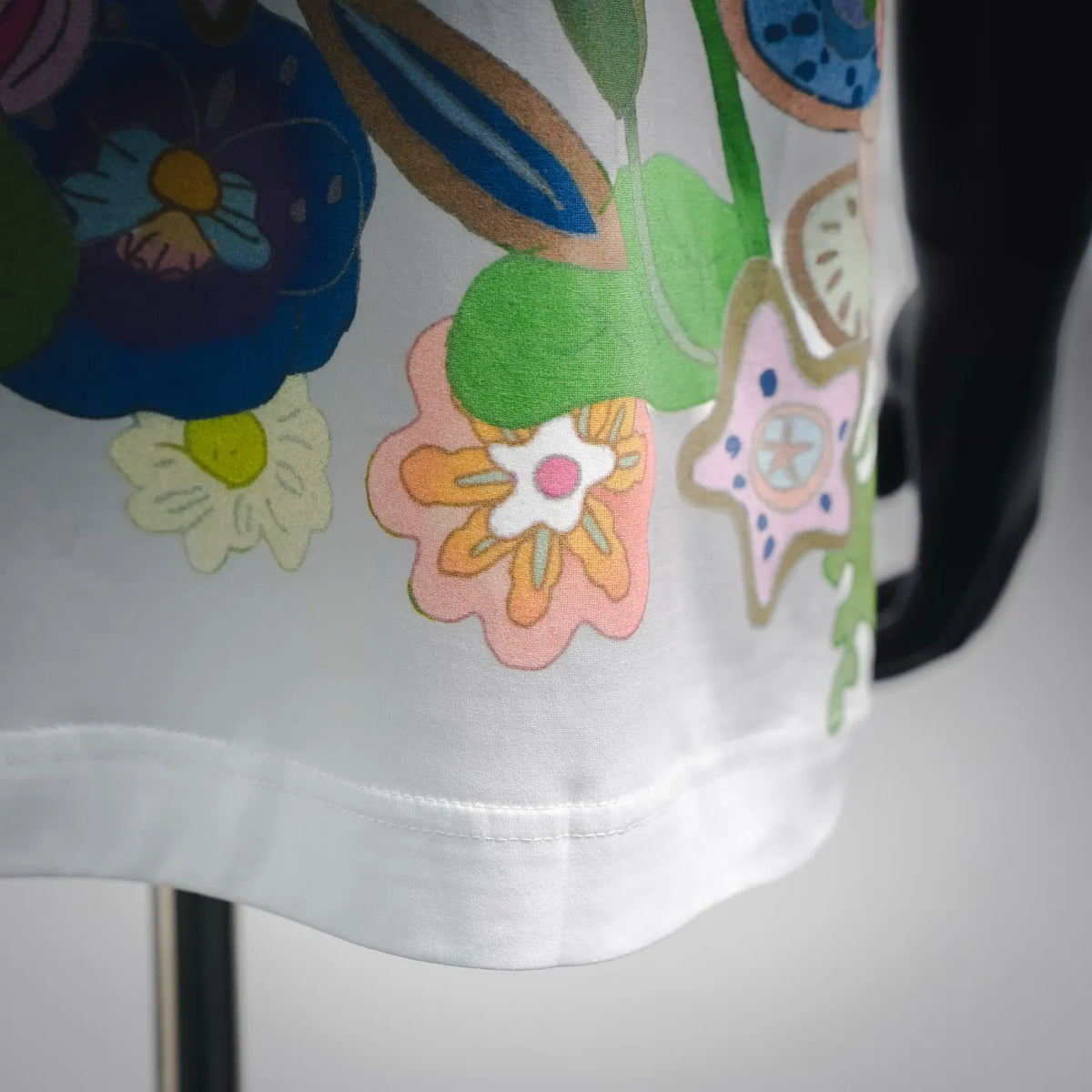 White T-shirt close-up of colorful floral graphics and stitched hem
