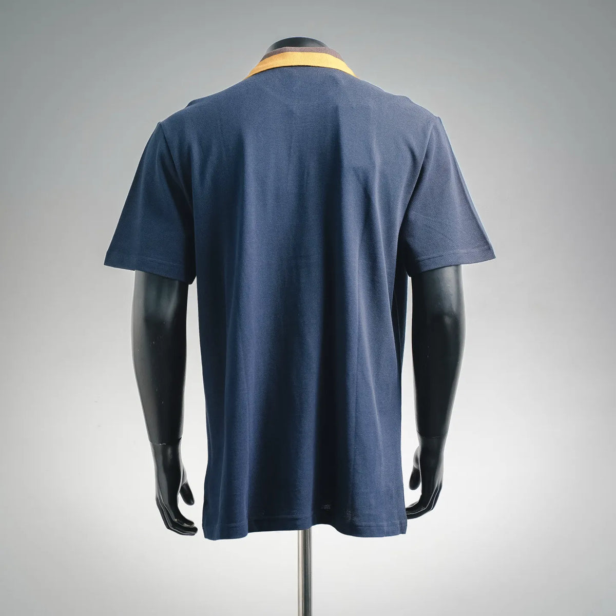 Navy polo shirt back view with short sleeves and yellow striped collar trim
