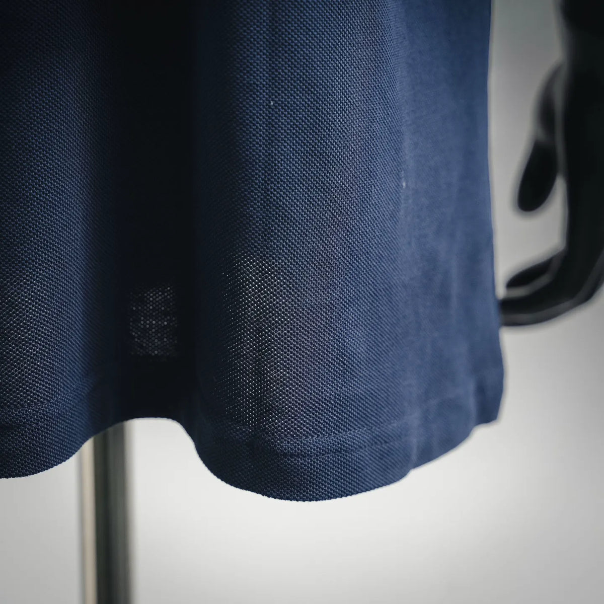 Close-up of navy polo shirt fabric texture with curved hem edge