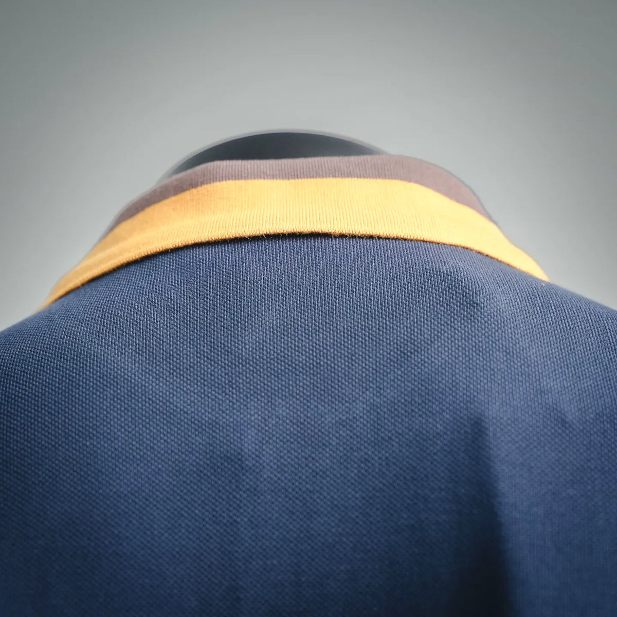 Polo shirt neckline with yellow striped collar trim on dark blue knit