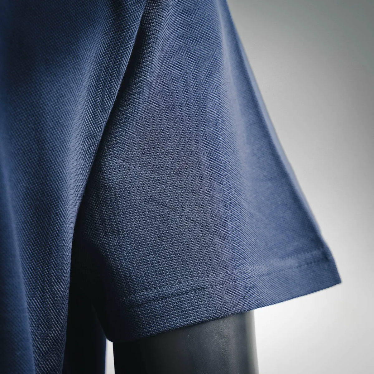 Short-sleeve cuff close-up on navy polo shirt with textured knit