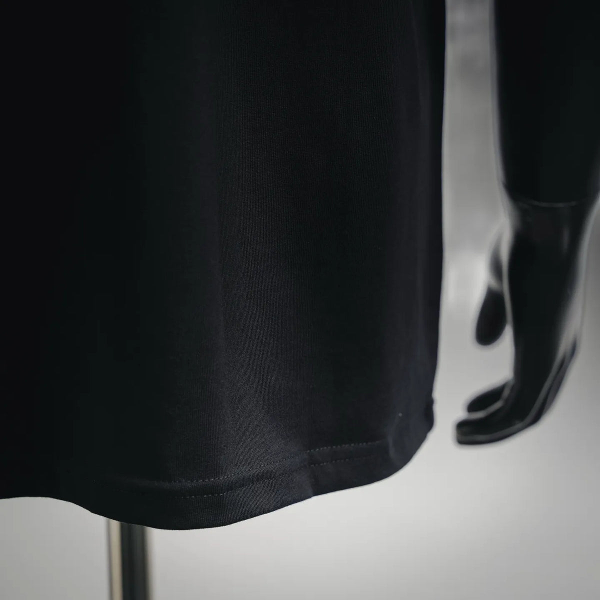 Black short-sleeve T-shirt hem with visible stitching