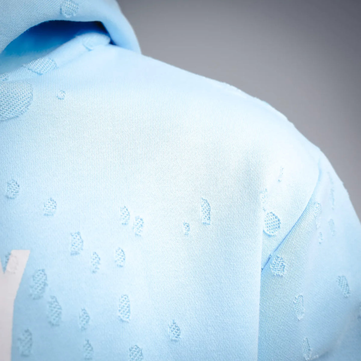Light blue hoodie fabric close-up with embossed pattern texture