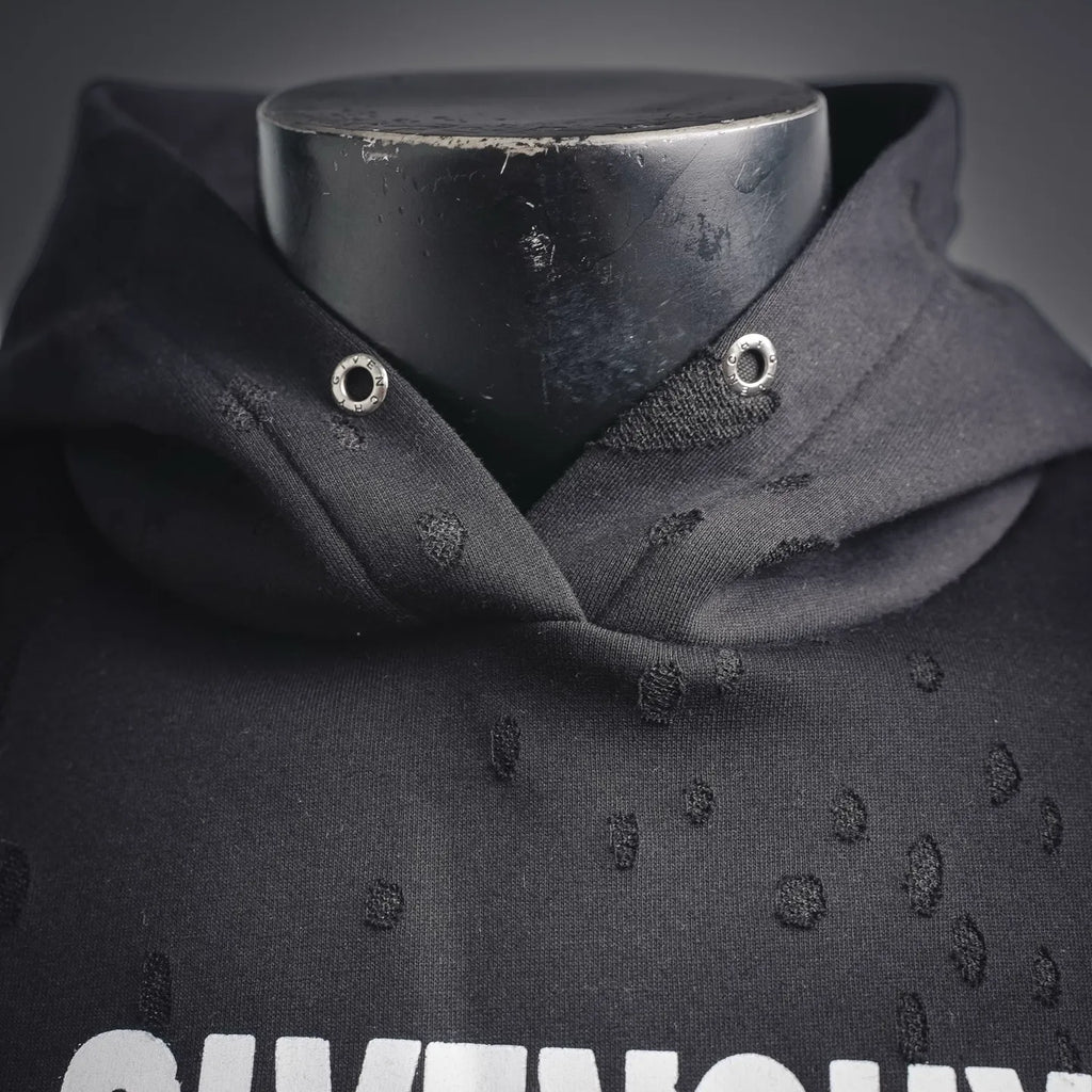 Front collar of black hooded sweatshirt with eyelet details and logo textured fabric