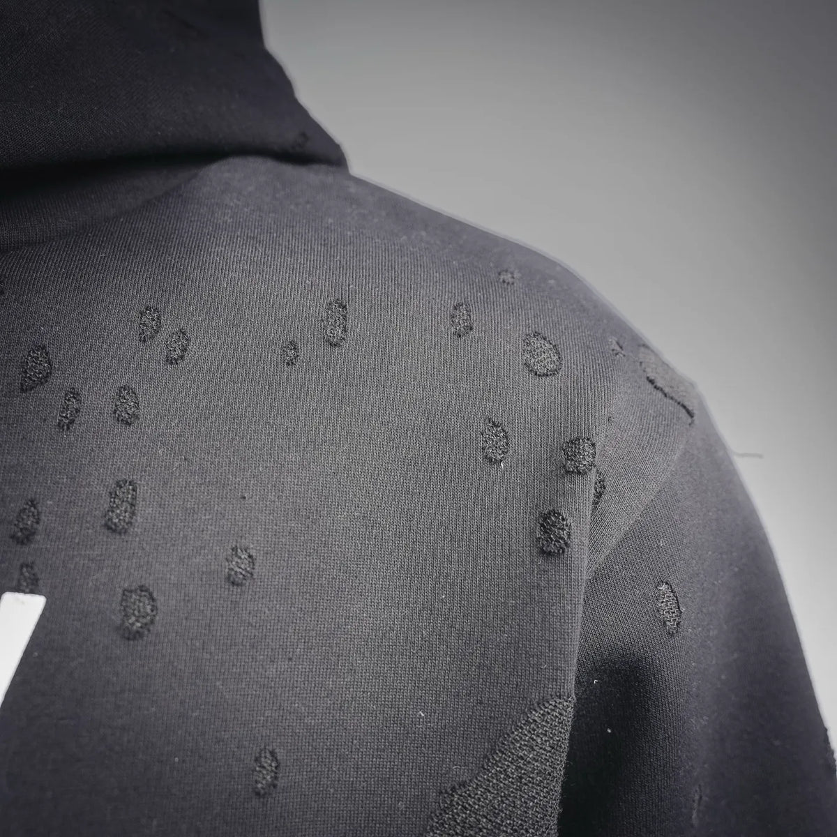 Close-up of black sweatshirt fabric with allover logo pattern on the sleeve