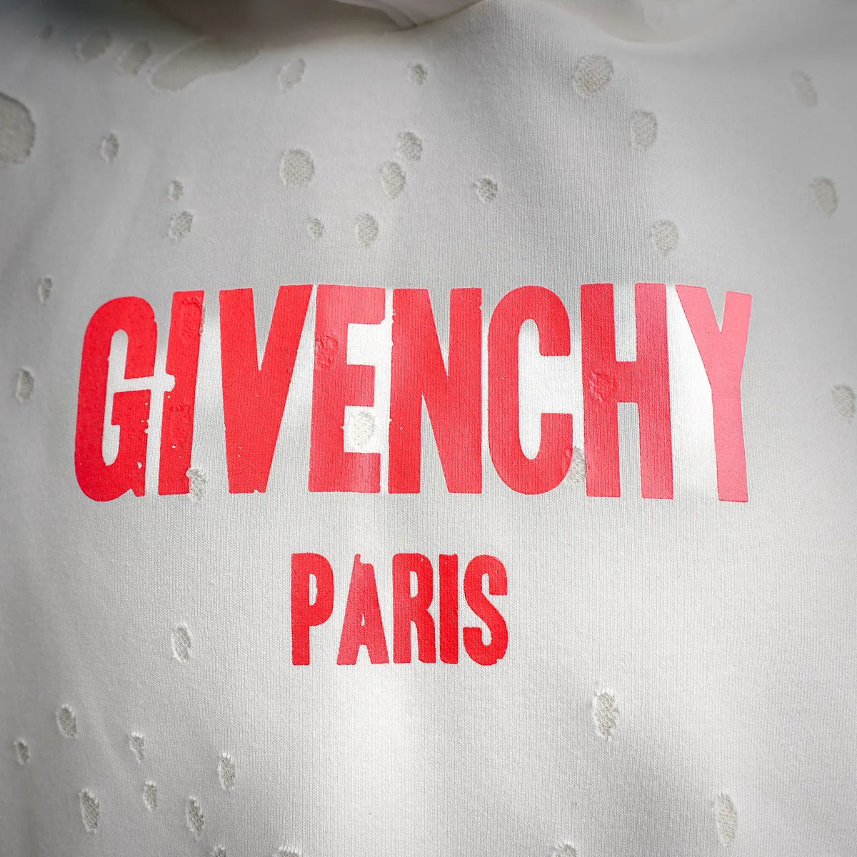 Close-up of red Givenchy Paris logo on white hooded sweatshirt