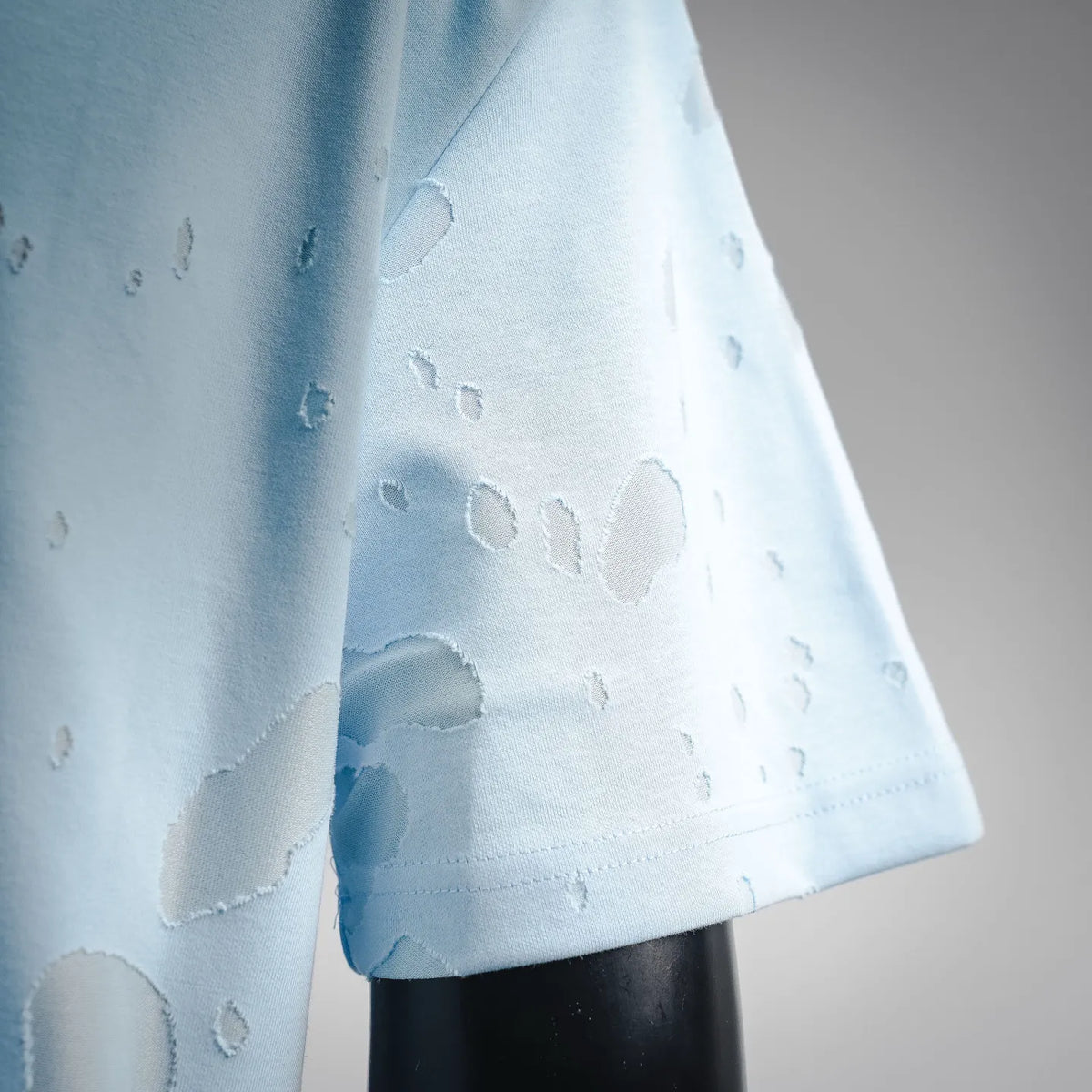 Light blue short-sleeve T-shirt with textured logo print across lower sleeve