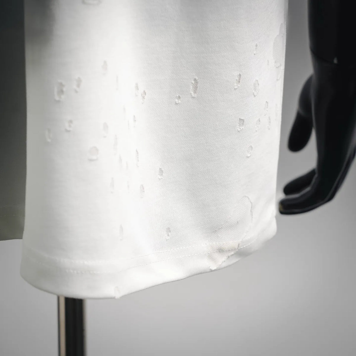 White T-shirt hem close-up with distressed fabric texture