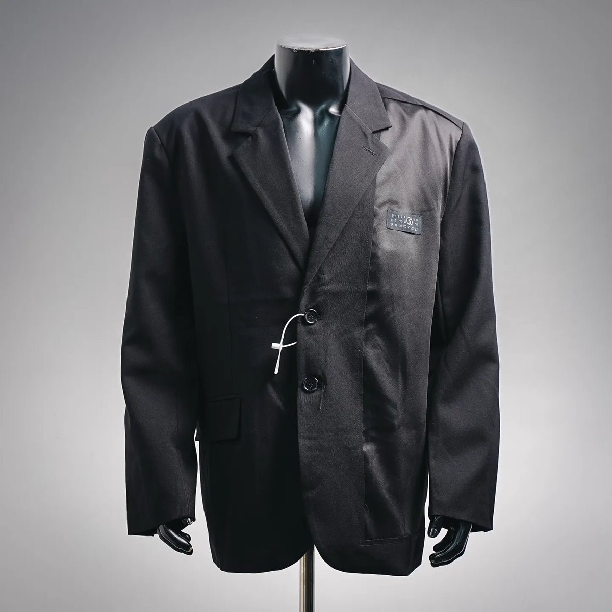 Black tailored coat with notch lapels, front buttons, and chest patch pocket