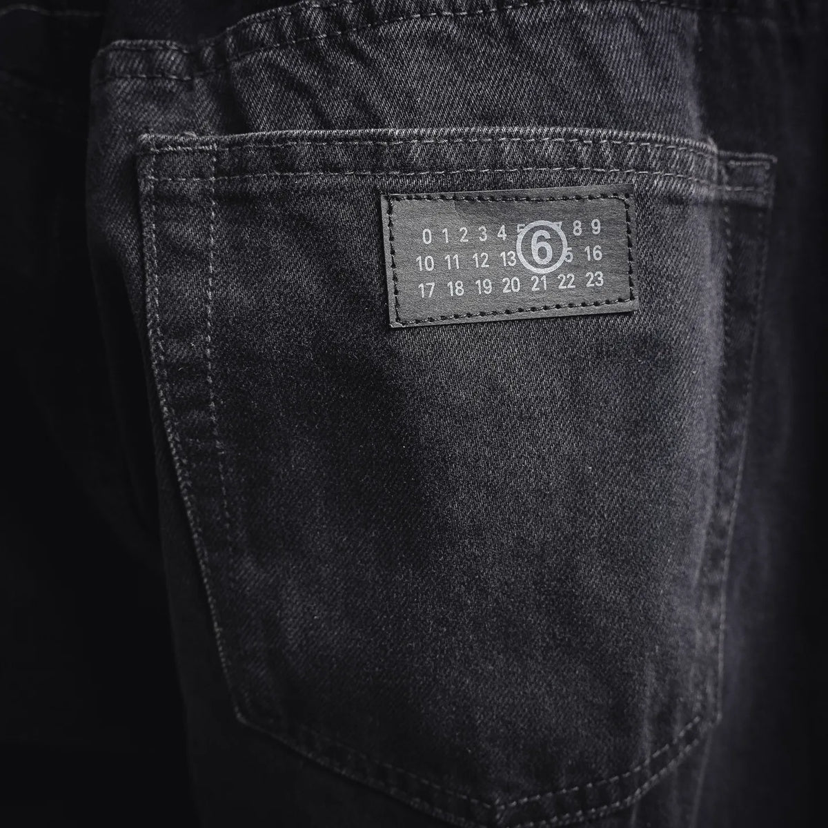 Back pocket on black denim pants with printed size code label.