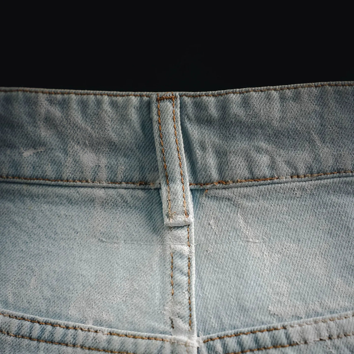 Denim pants crotch and waistband seam detail with central bar tack stitching