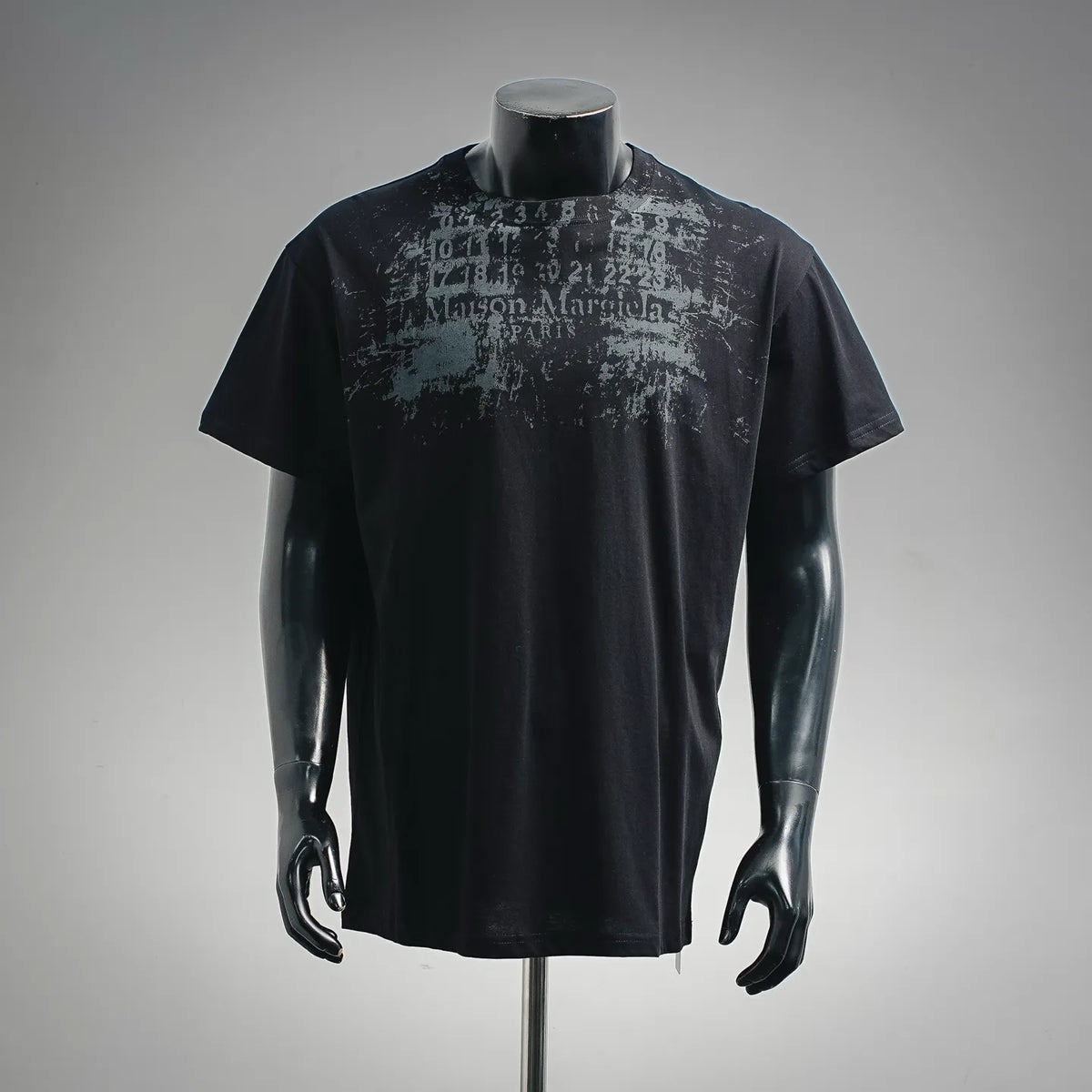 Black short-sleeve T-shirt with distressed Maison Margiela logo graphic at chest