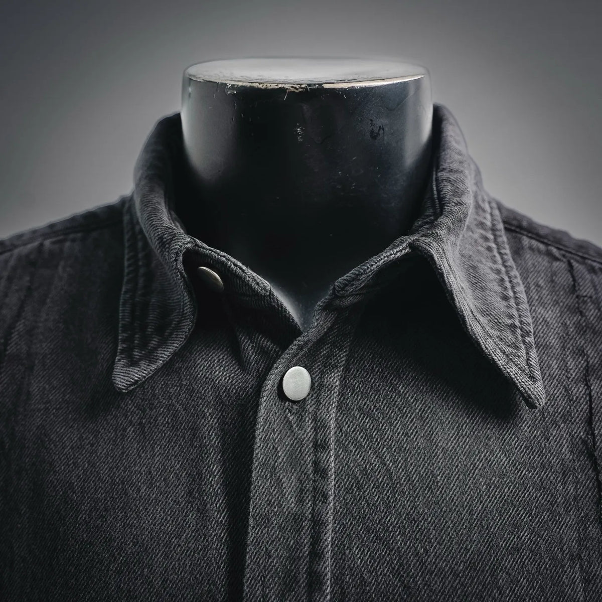 Black denim shirt close-up: pointed collar with round button at the placket