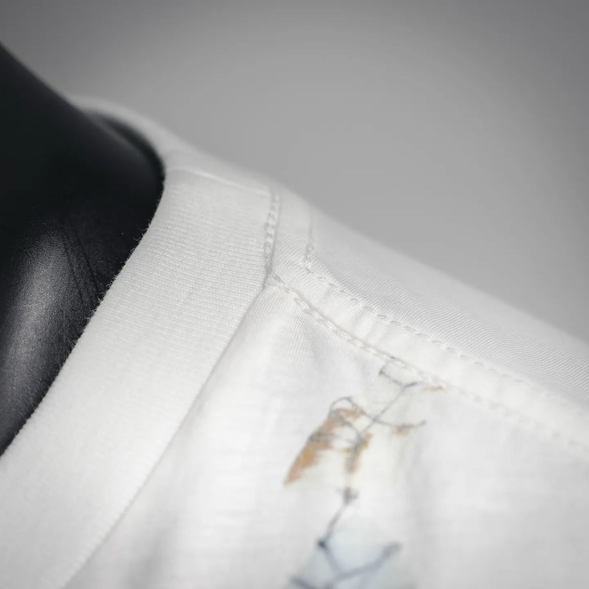 White T-shirt fabric close-up with stitched edge and blue-gold print motif