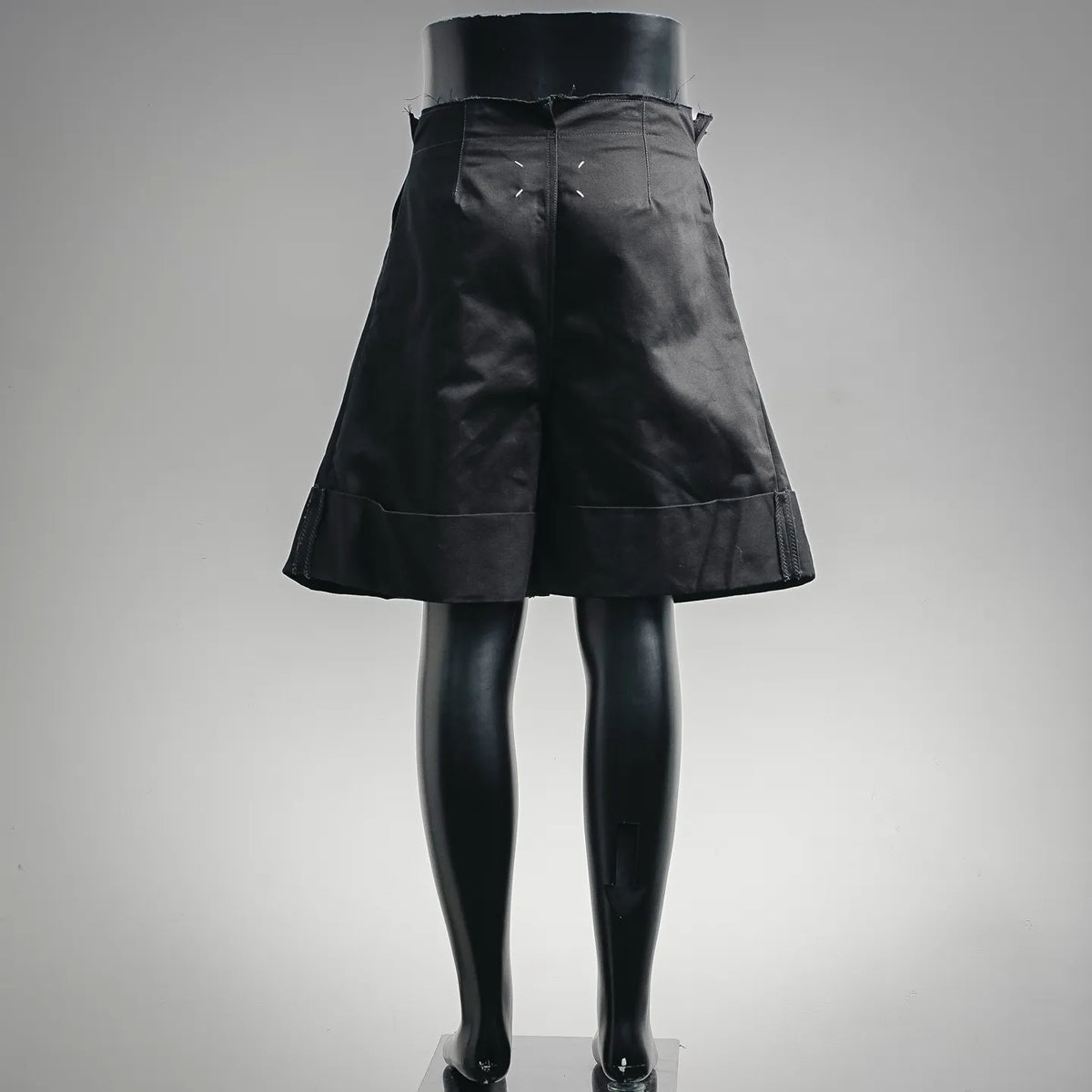 Black shorts-style pants with wide waistband and flared hem.