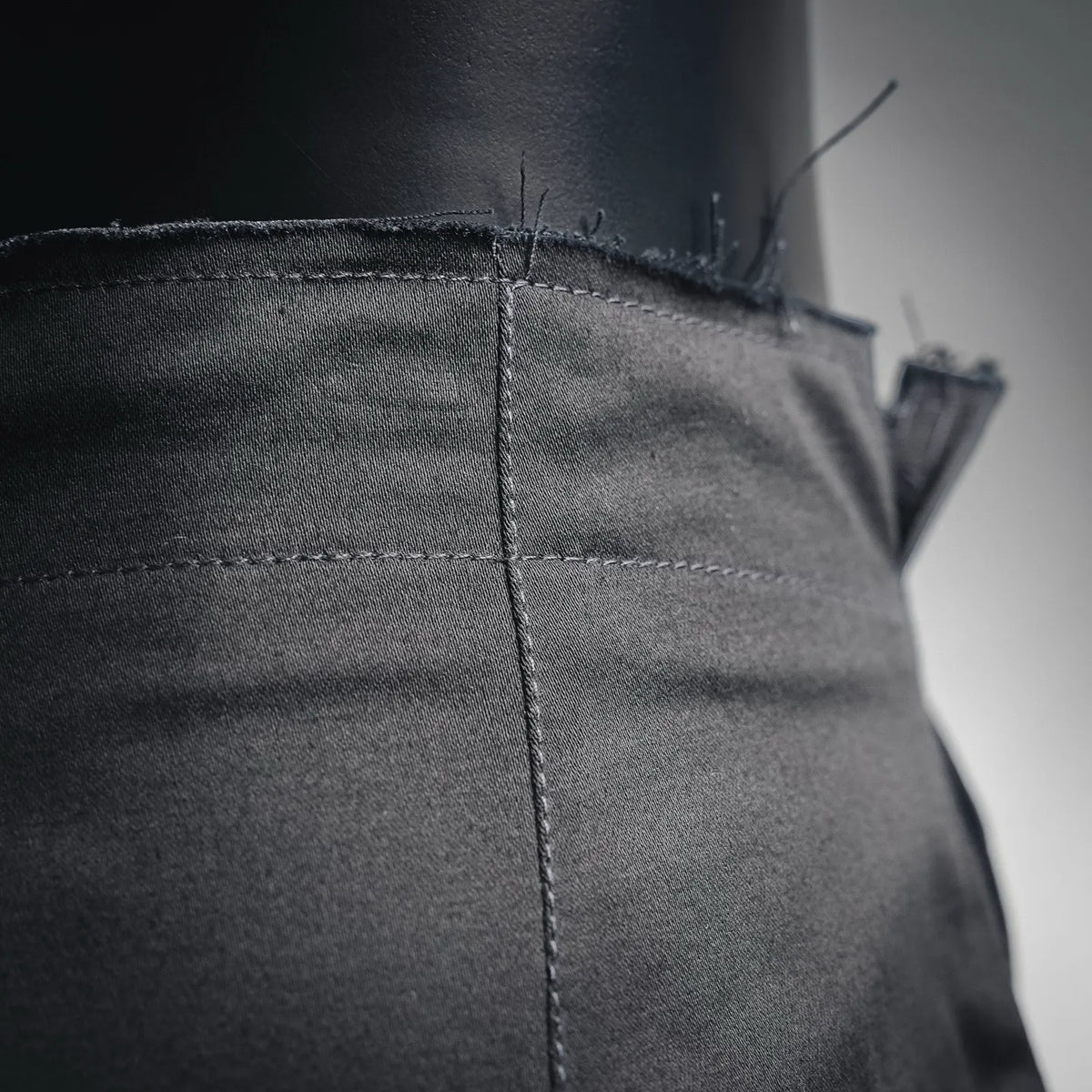 Black pant panel with visible seam stitching and edge trim.