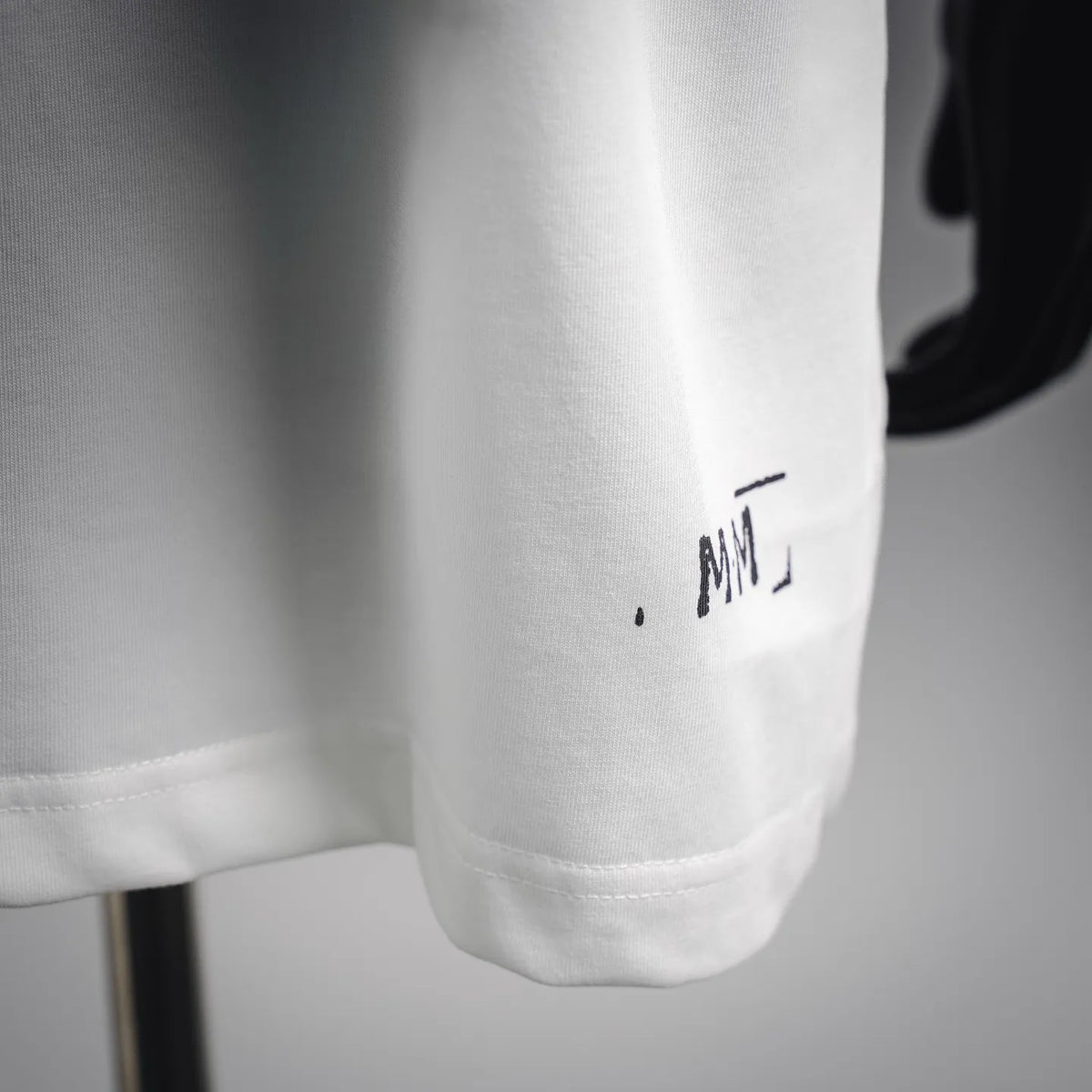 Maison Margiela white T-shirt sleeve cuff with small printed mark near the hem