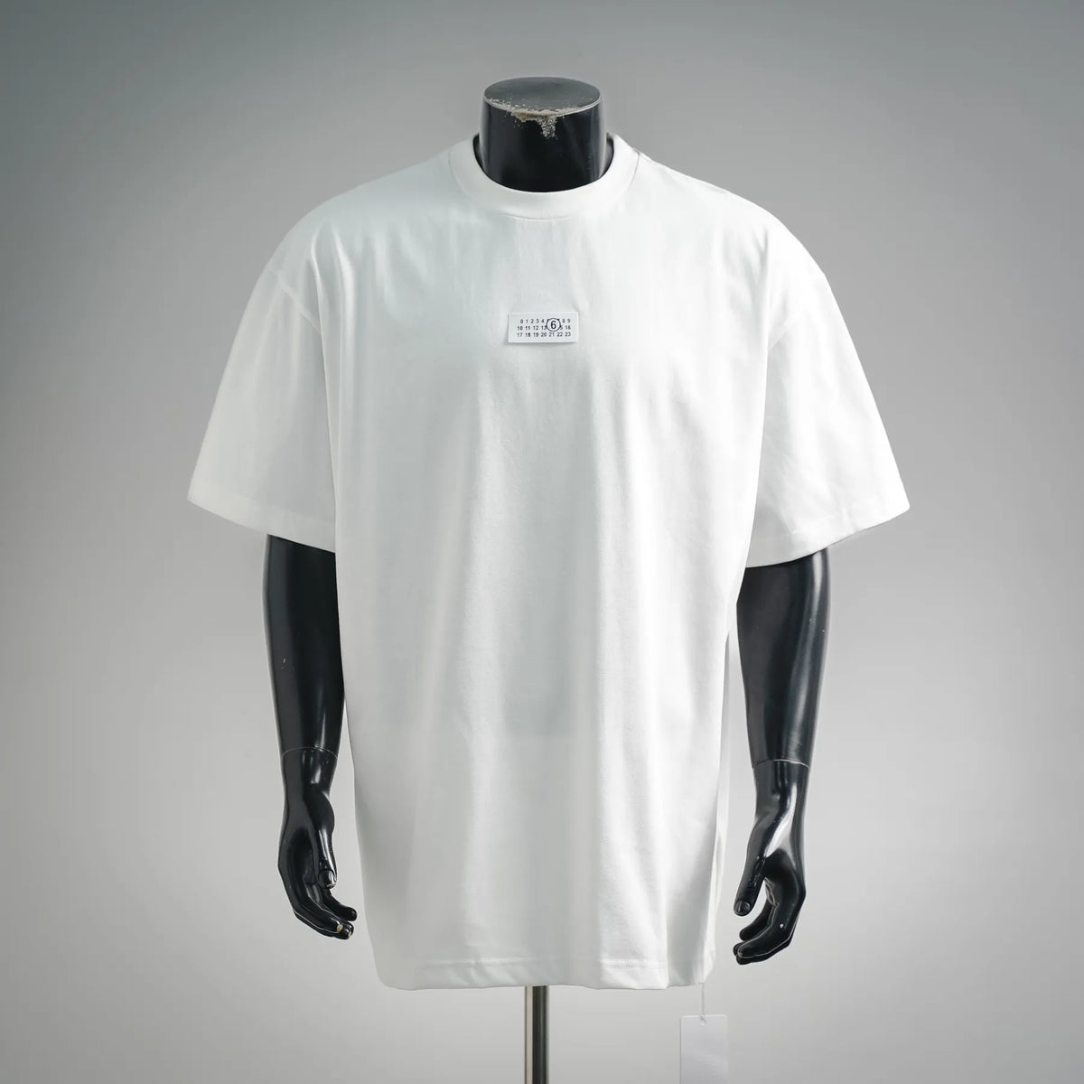 White crew-neck T-shirt on mannequin with small logo label at center chest