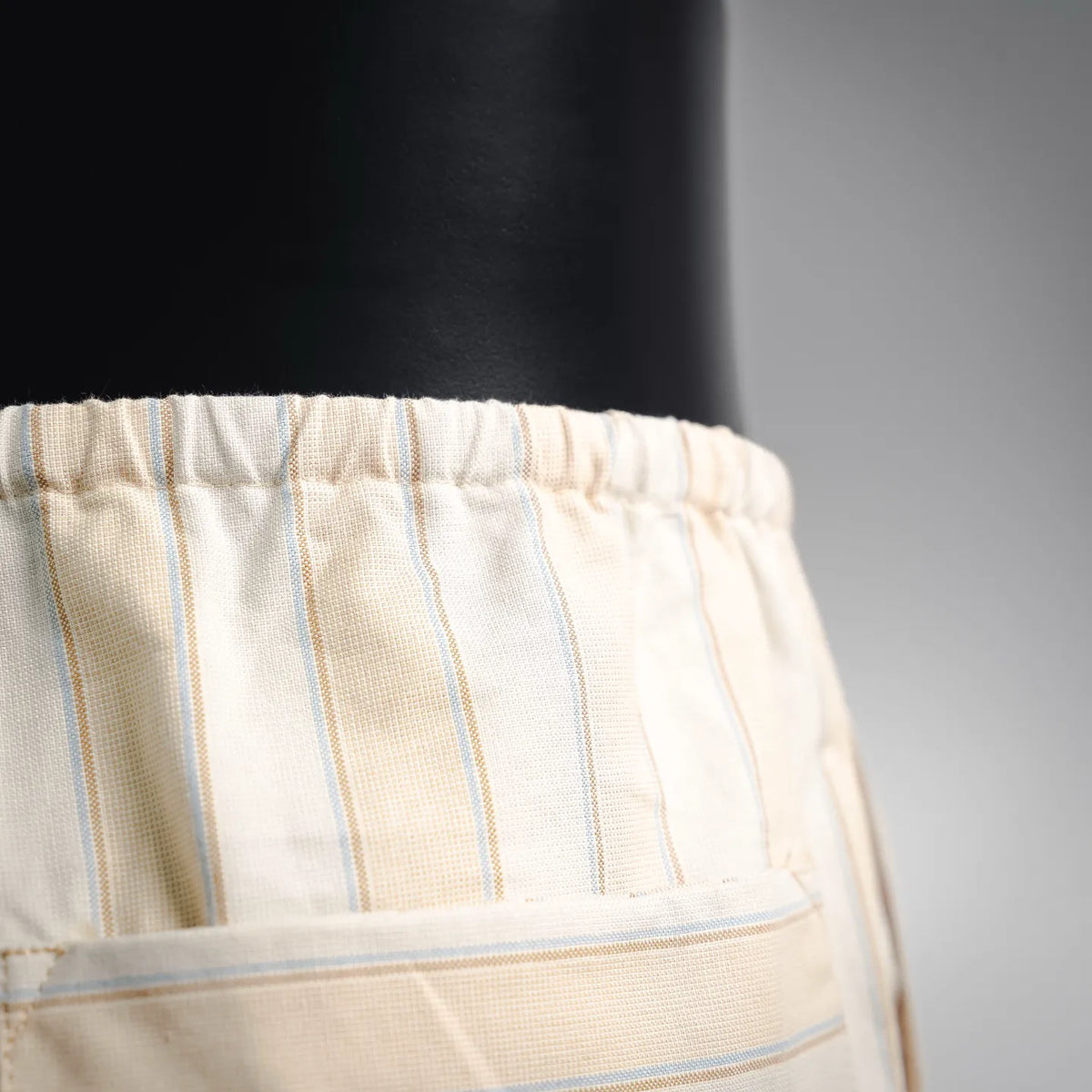 Cream striped pants close-up: elastic waistband with light blue vertical lines
