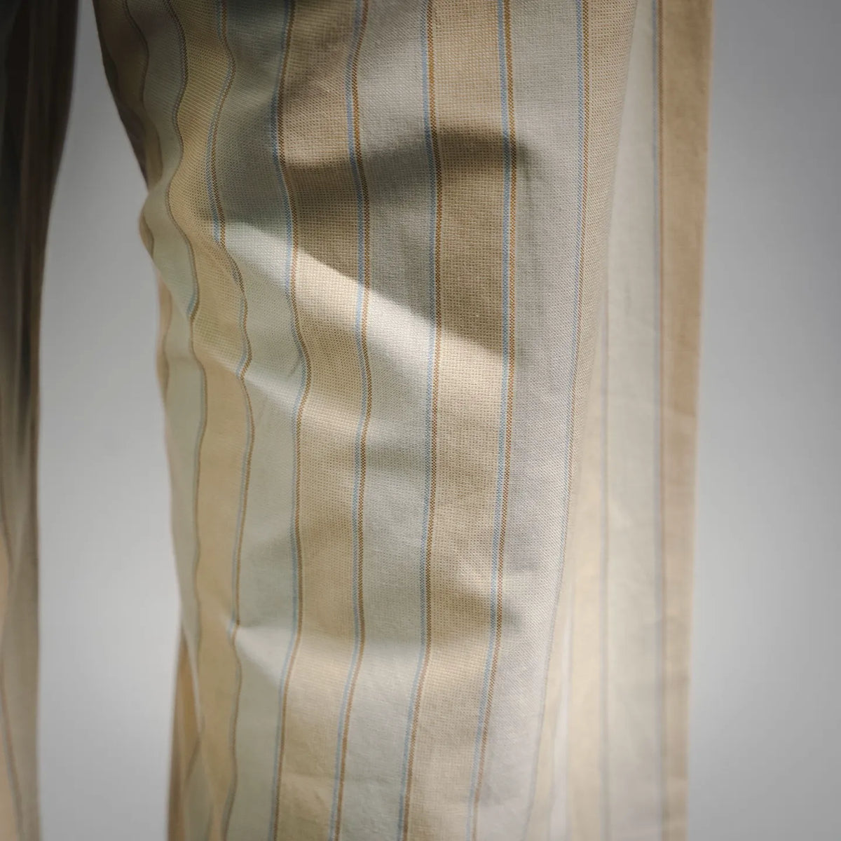 Cream and light blue striped pants fabric close-up, vertical stripe pattern