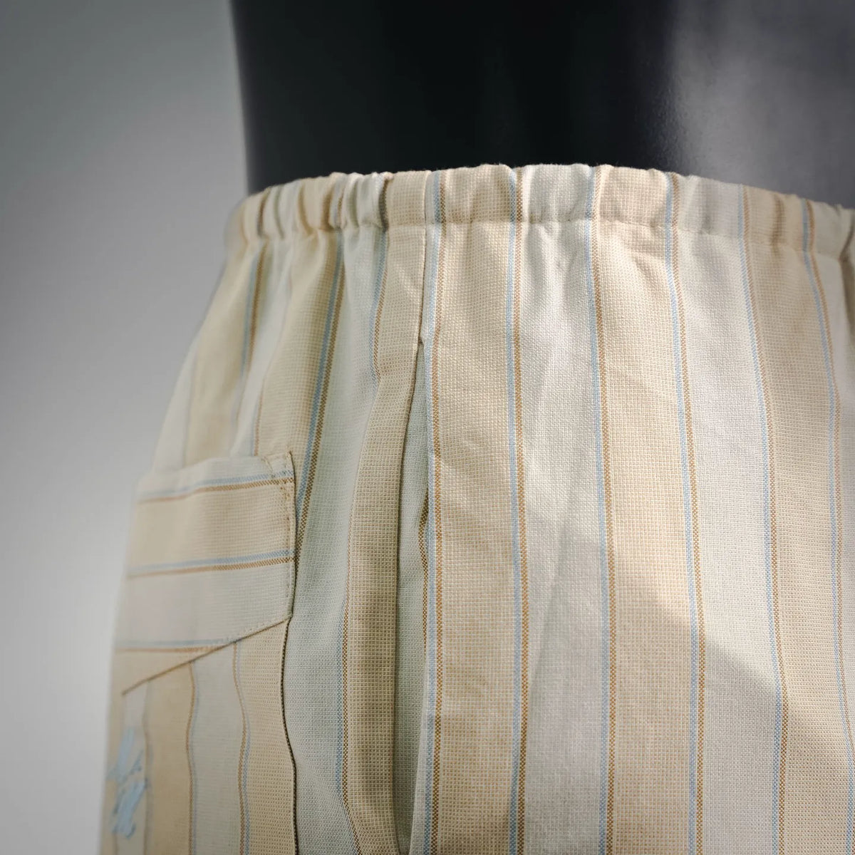 Cream striped pants with elastic waistband and side pocket seam detail
