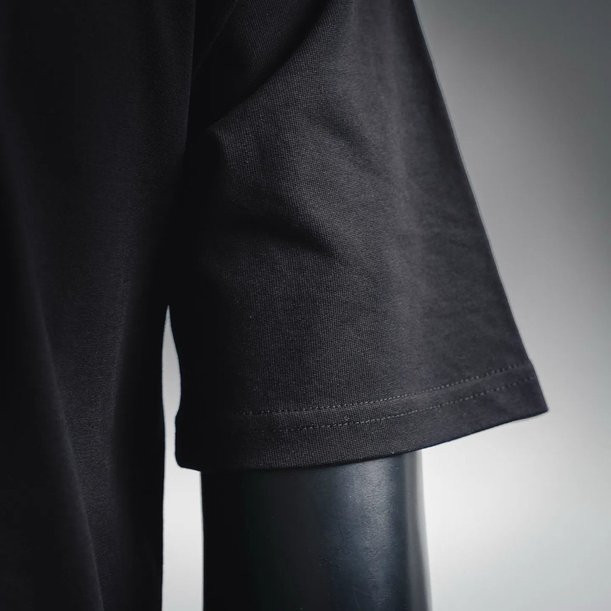 Black T-shirt sleeve cuff with stitched hem and textured knit fabric