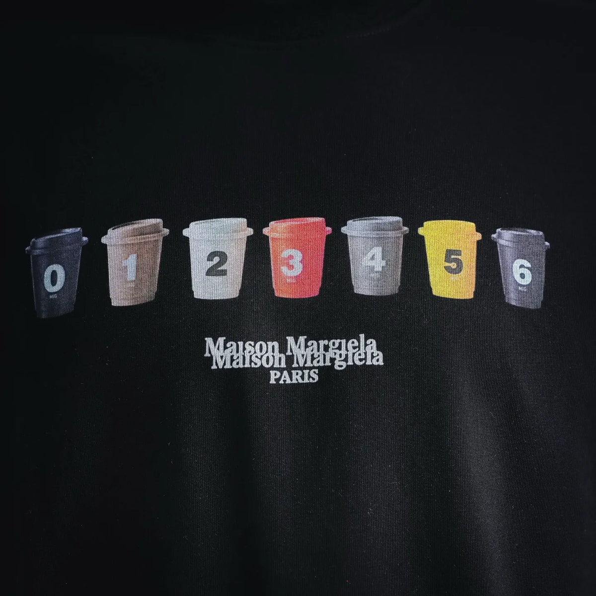 Black T-shirt chest print: numbered cup icons and Maison Margiela Paris logo