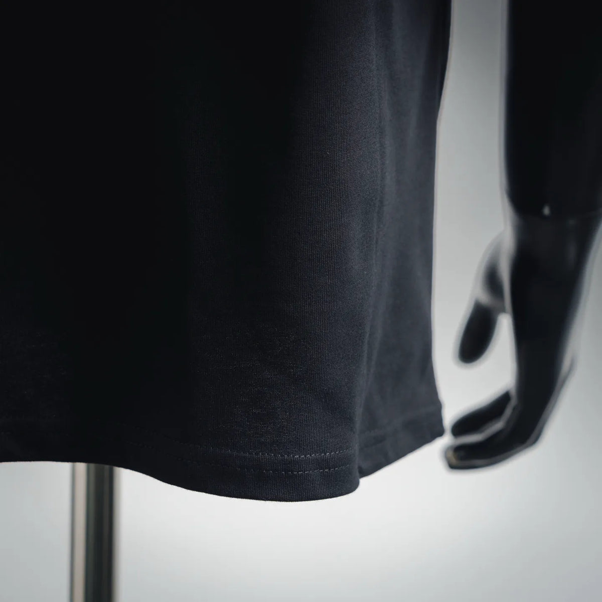 Black short-sleeve T-shirt with visible stitched bottom hem