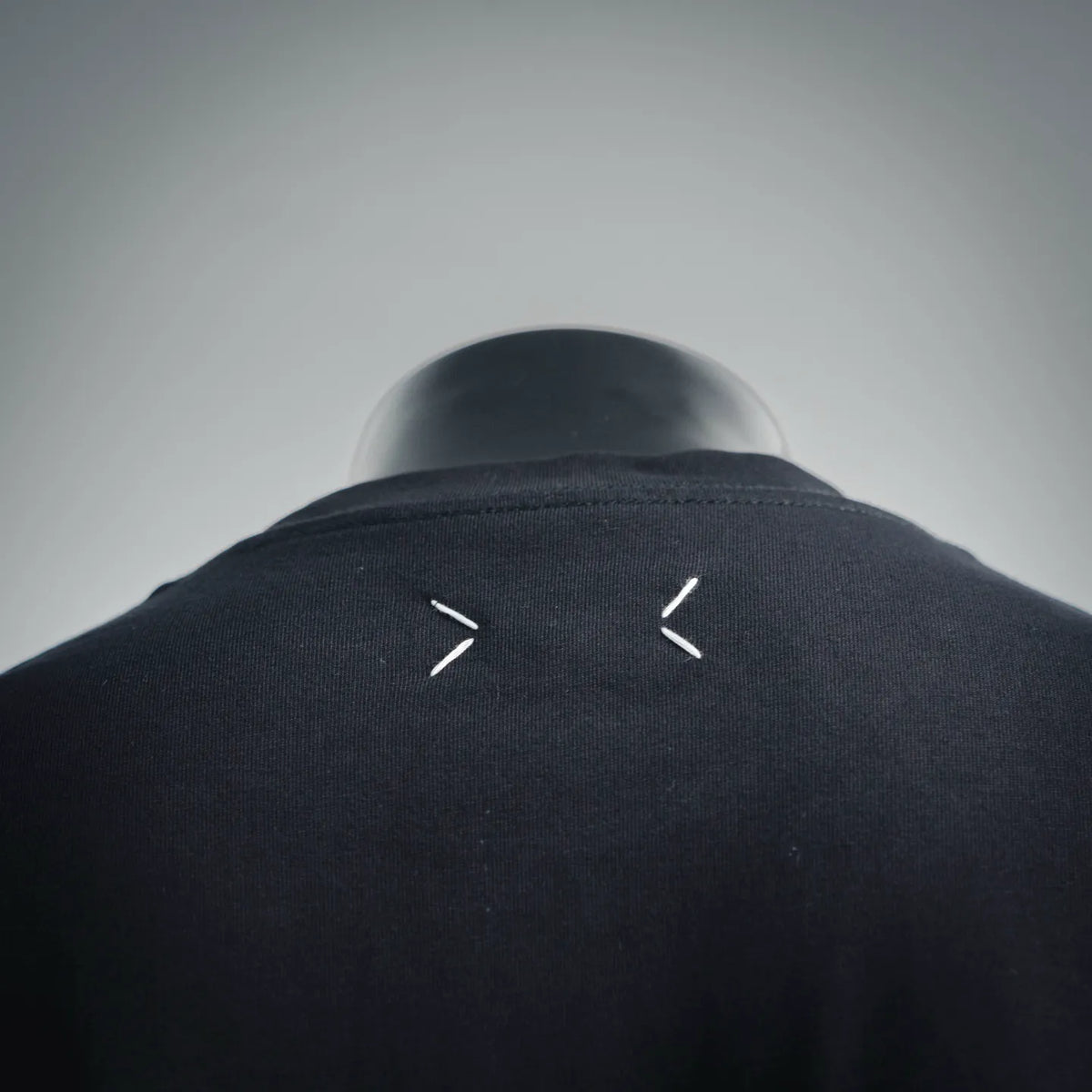Black T-shirt collar back with small white V-shaped logo