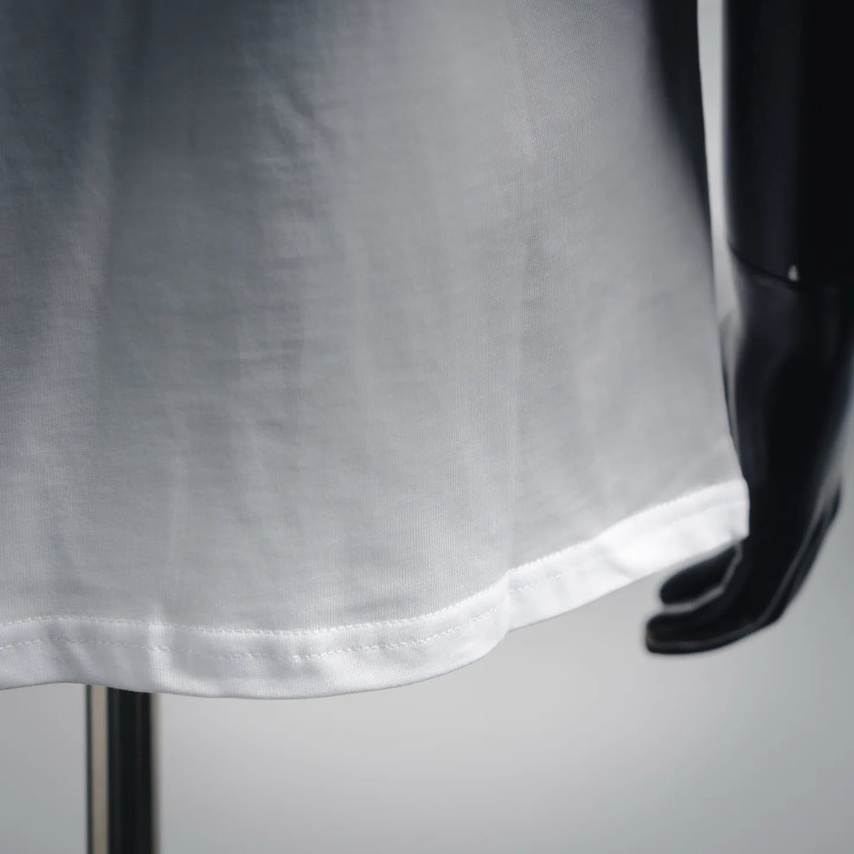 White T-shirt hem close-up with stitched bottom edge and fabric texture
