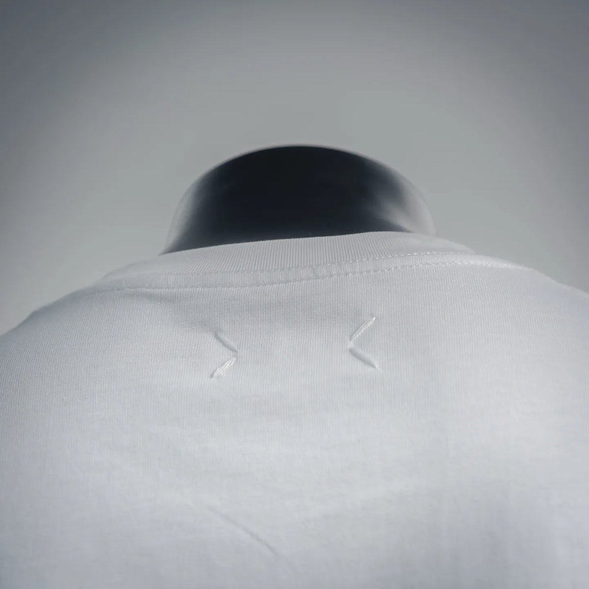 White T-shirt collar close-up with small stitched details at neckline